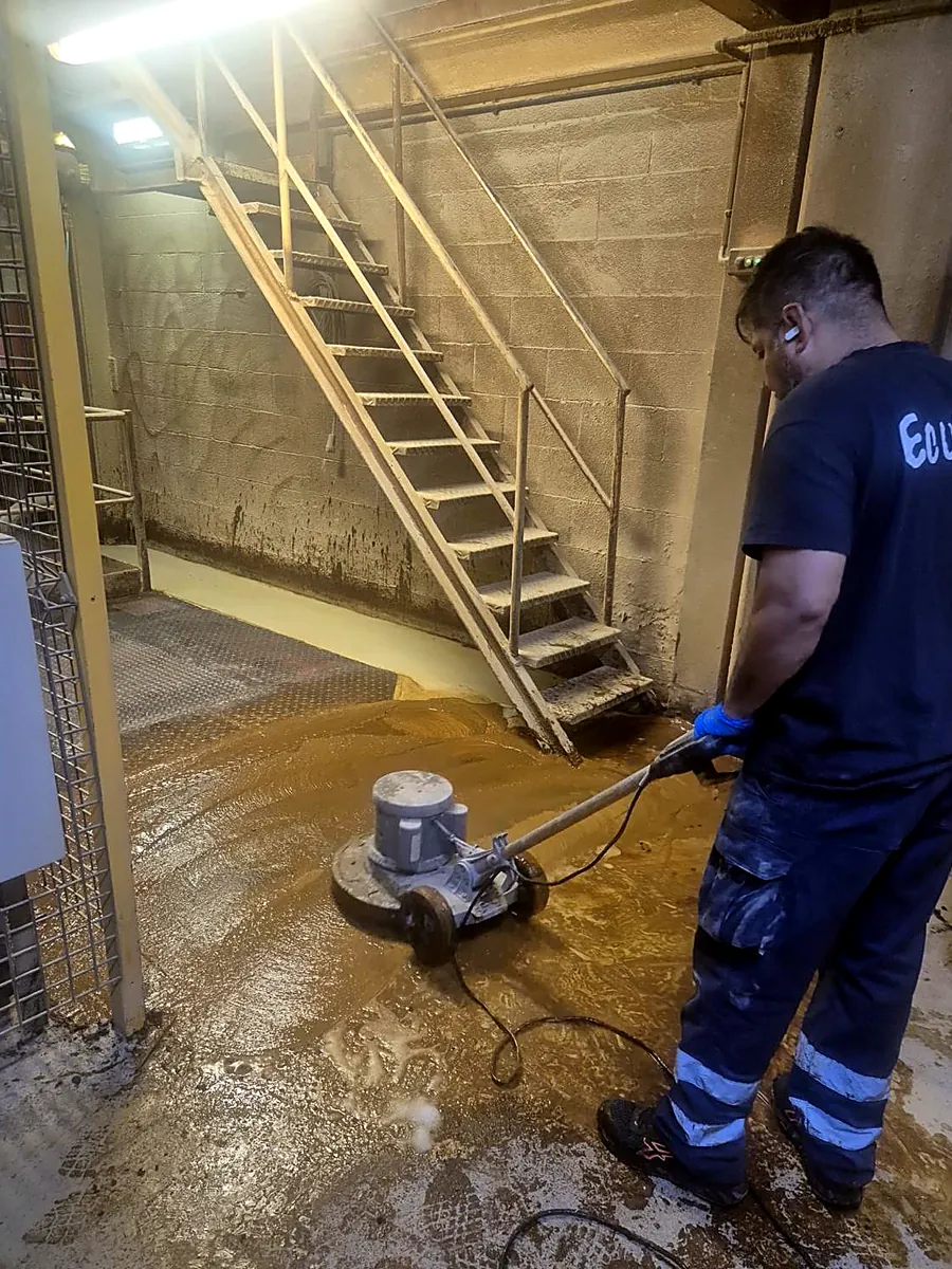 Técnico trabajando con máquina rotativa en nave industrial